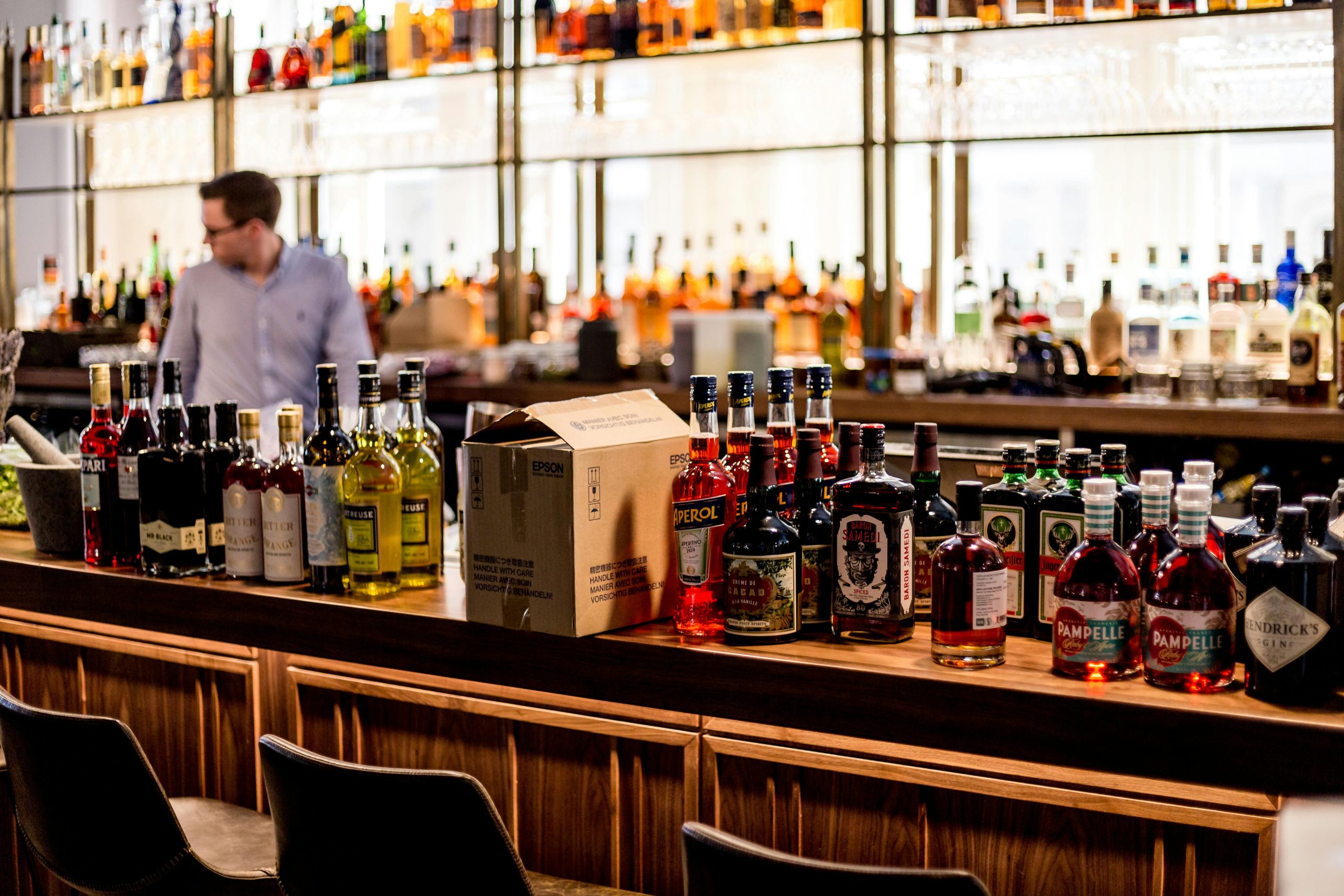 Vibrant bar scene showcasing an assortment of liquor bottles with a bartender in the background.